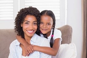 Mother and Daughter Hugging on Couch 